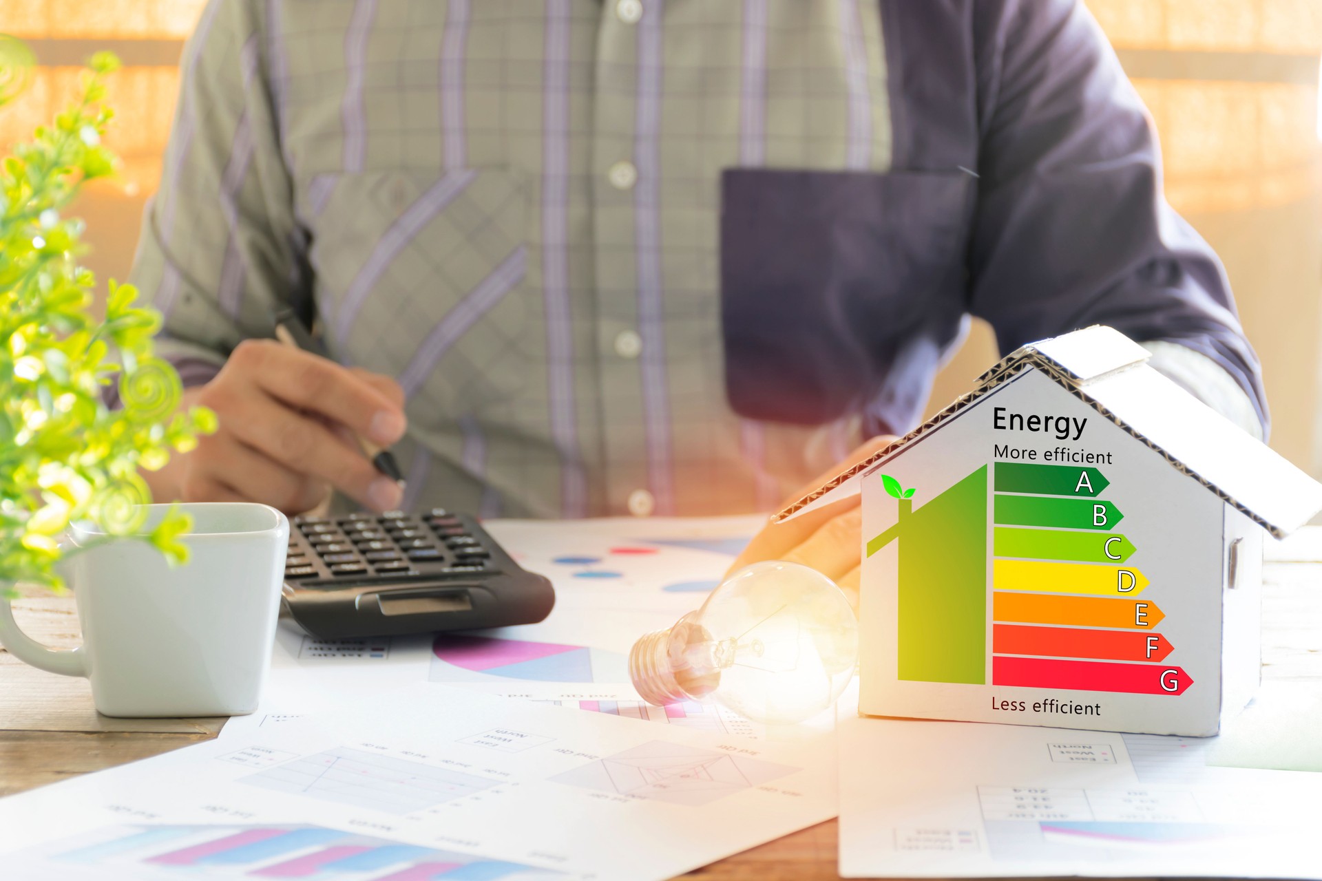 Men who are calculating cost savings from energy. Hand holding a pen.