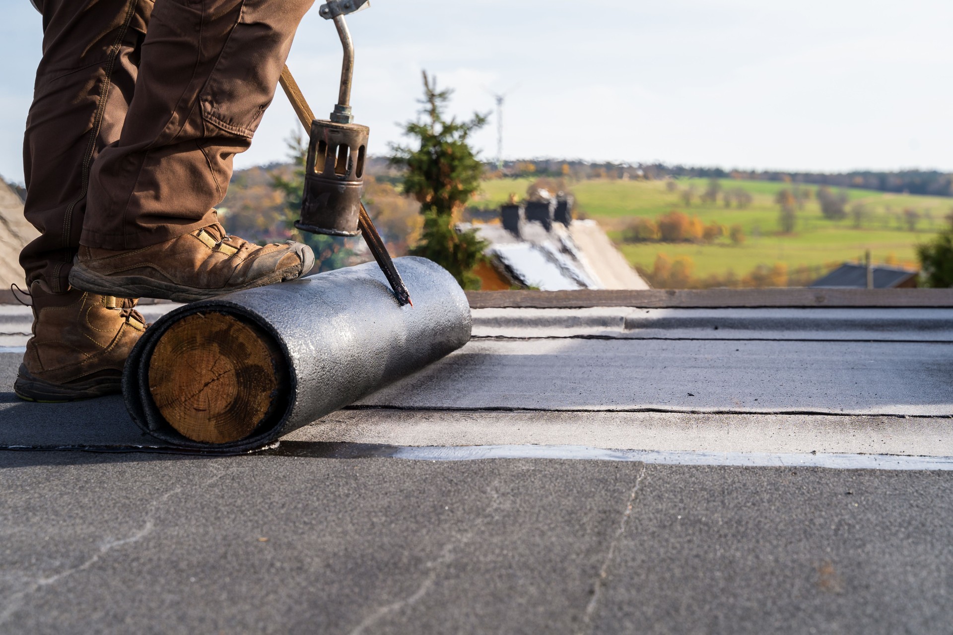 Worker Heating and melting bitumen roofing Flat roof installation.